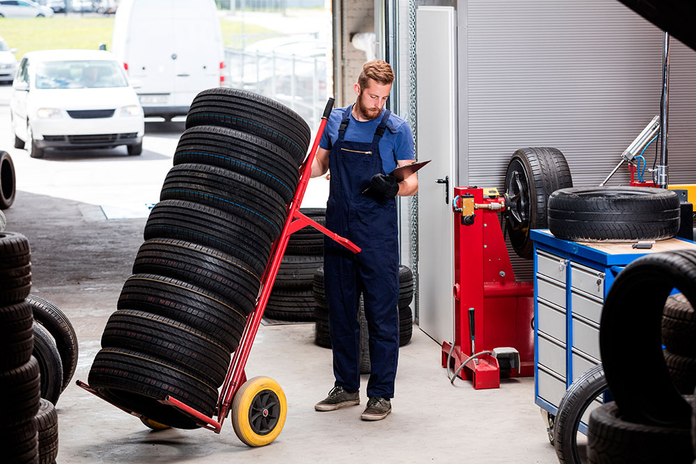Man With Stack of Tires On Dolly